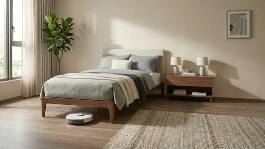 Wooden bed frame with raised legs and robot vacuum cleaning underneath in a warm Singapore bedroom.