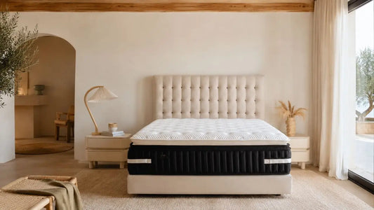 Calm Italian-inspired bedroom with tufted beige headboard, white quilted mattress, warm neutral styling, and soft natural daylight