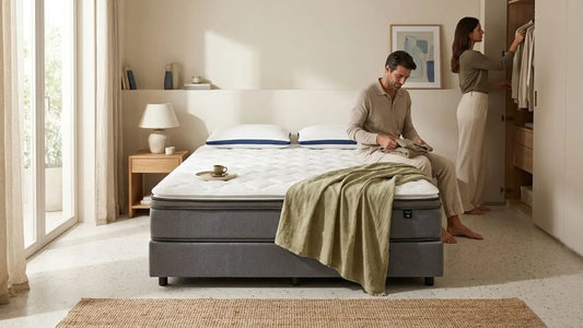 Couple in a calm bedroom with a mattress topper on the bed, showing how the right topper can refresh an older mattress and improve everyday comfort.