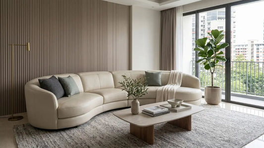 Curved cream sofa in a modern Singapore condo living room with balcony windows, round-edge coffee table, neutral rug, and soft natural light.