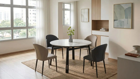 Round extendable dining table with mixed upholstered chairs in a bright Singapore HDB dining area