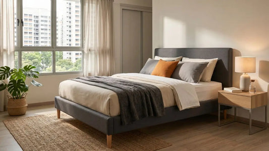 Grey upholstered bed frame with neatly styled mattress in a bright Singapore HDB bedroom, showing a well-maintained sleep setup for long-term mattress use