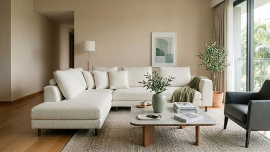 Italian-inspired Singapore living room with warm neutral walls, ivory sectional sofa, timber flooring, stone coffee table, and soft botanical accents.