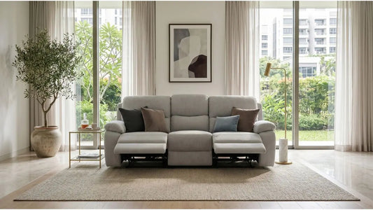 Light grey velvet recliner sofa in a bright Singapore living room with large windows, neutral rug, and indoor plants