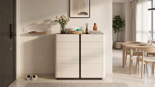 Cream living room storage cabinet styled in a Singapore home entryway with flowers, books, and neutral décor beside a dining area.
