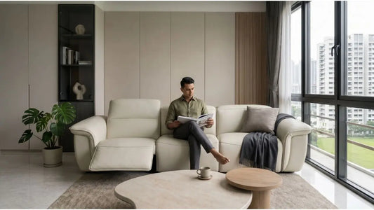 Man reading on a cream recliner sofa in a rental-friendly Singapore living room with neutral furniture and city view