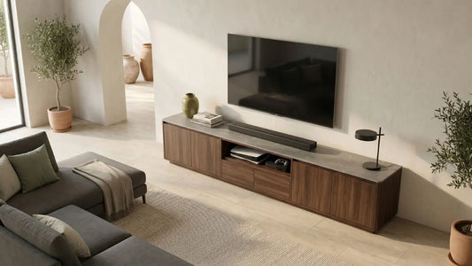 Modern wooden TV console with soundbar and wall-mounted television in a warm living room with sofa seating