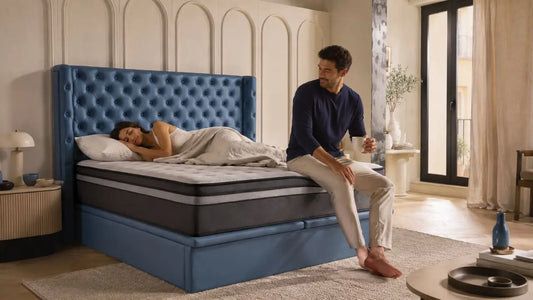 Couple relaxing on a blue tufted bed with a motion isolation mattress in a warm editorial bedroom setting