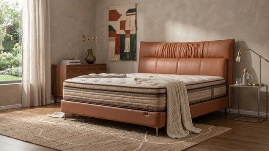 Queen bed in a warm Singapore bedroom with tan leather bed frame, layered bedding, bedside storage, and natural daylight.