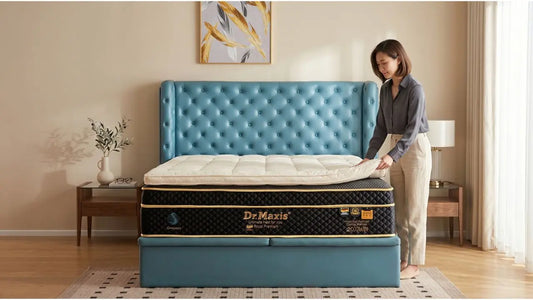 Woman adjusting a quilted mattress topper on a premium mattress with teal upholstered bed frame