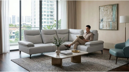 Man reading on a light grey sectional sofa with firm supportive cushions in a modern Singapore living room.