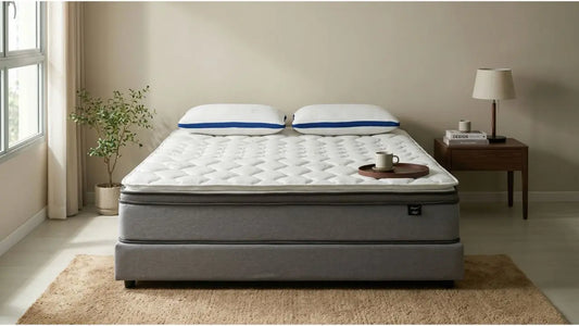 White quilted mattress on a grey bed base in a minimalist Singapore bedroom with pillows, bedside table, rug, and natural light
