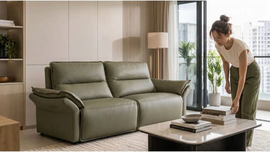 Woman styling books on a marble coffee table beside an olive green sofa in a modern Singapore first-home living room